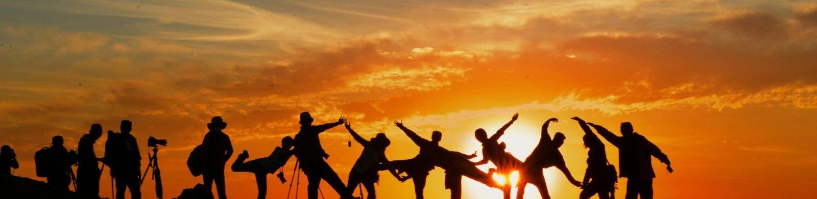 Group of people silhouetted against a vibrant sunset, showcasing unity and joy.
